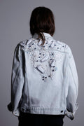 A person wearing the oversized Pinball Denim Bomber Jacket in 'Ice' blue. The jacket features a slouchy 80s-style cut with dropped shoulders and a striking pattern of oversized geometric ornaments across the back and sleeves.