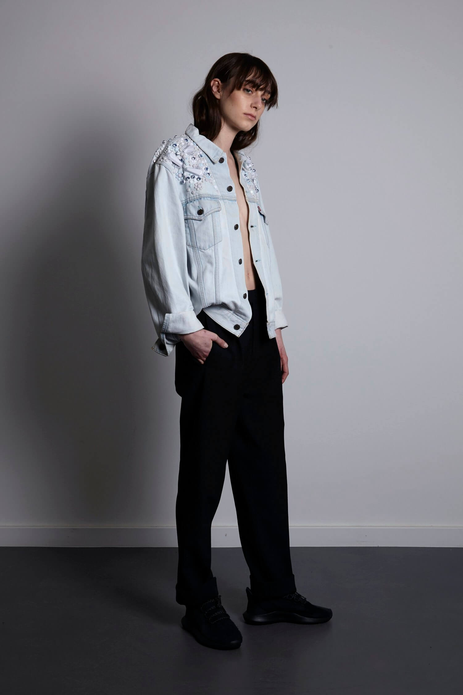 A lifestyle image of a model in a relaxed pose wearing the vintage Levi's Pinball Bomber. The ice-colored embellishments catch the light, highlighting the contrast between the rugged denim texture and the avant-garde glass ornaments.