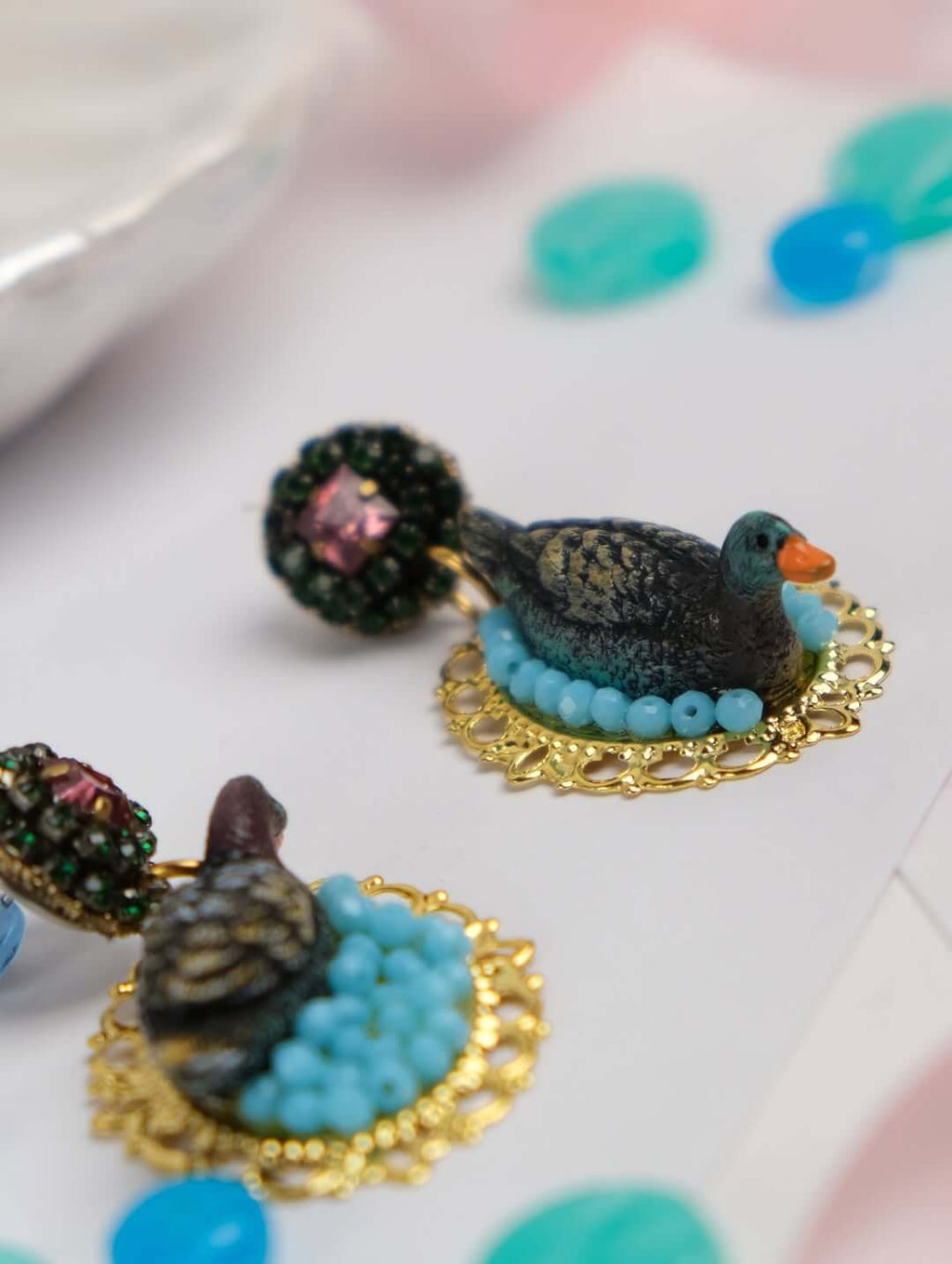 Nahaufnahme der „Wild Rose“ Ohrringe mit detailgetreuen Vögeln aus Resin, umrahmt von filigranen Glasperlen und funkelnden D&G Swarovski-Kristallen.