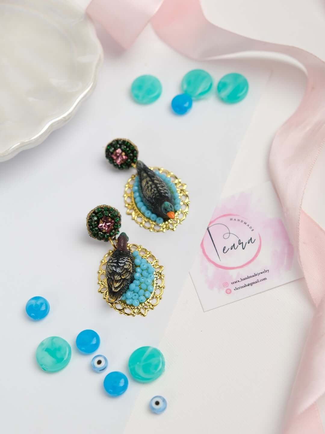 Die „Wild Rose“ Kollektion von NOUS: Ein Paar handgefertigte Ohrringe auf neutralem Hintergrund, die den Kontrast zwischen Boho-Stil und luxuriösem Swarovski-Glanz betonen.