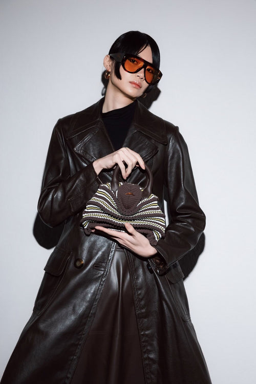Model trägt die gestrickte Balom Attesa Leder Handtasche mit Goldkette in Urban Jungle bei NOUS Studio